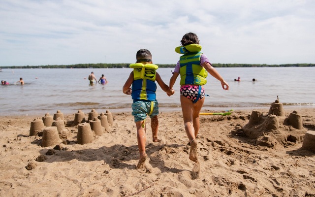 Image showing two children running past sand castles as they head for a swim into the lake.